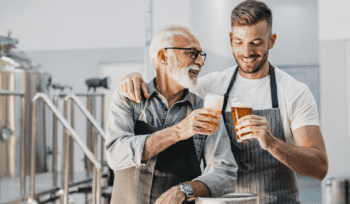 Older and younger man cheers with a beer